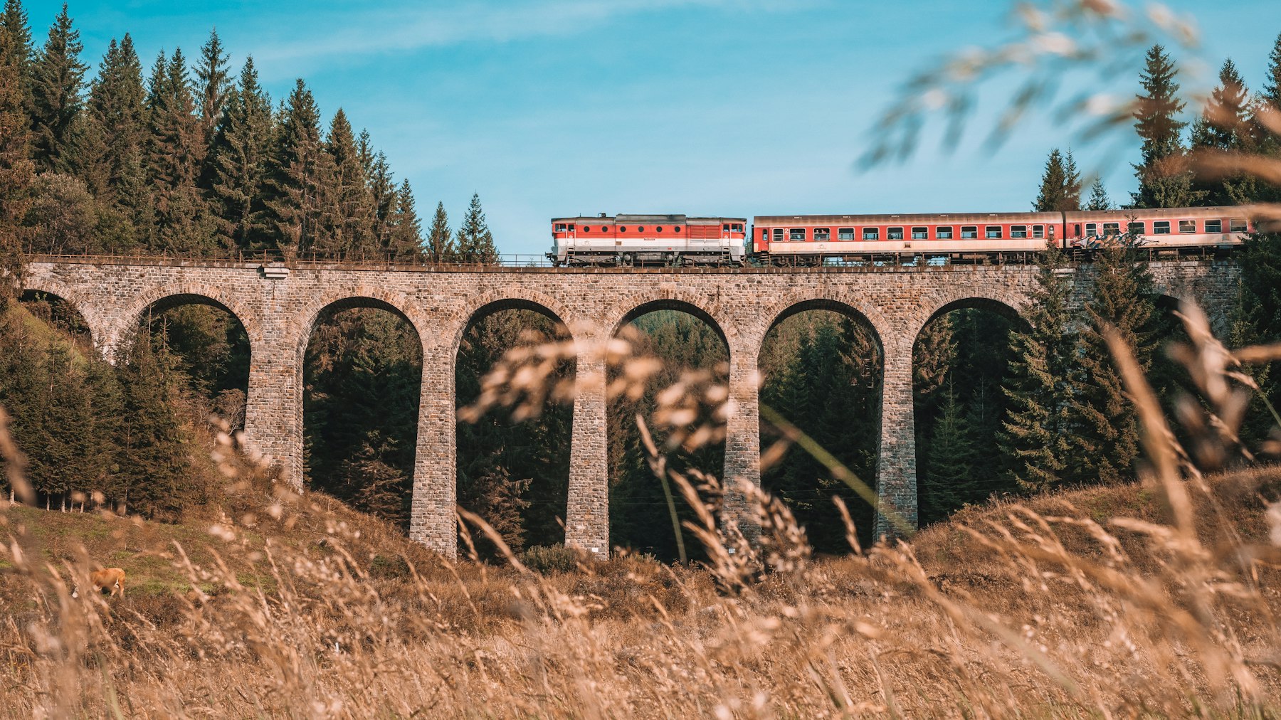Passenger train crossing a masonry rail viaduct
