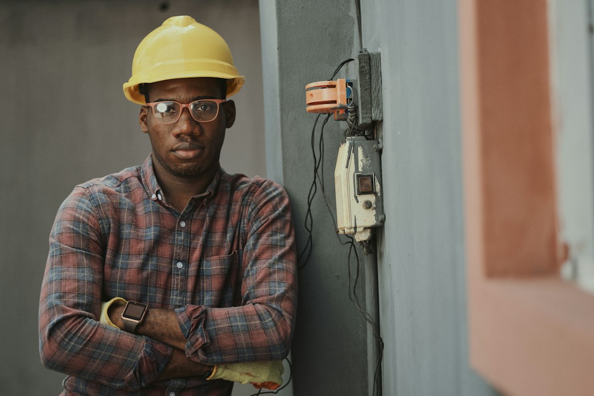 Engineer in a yellow hard hat standing at a site switchboard